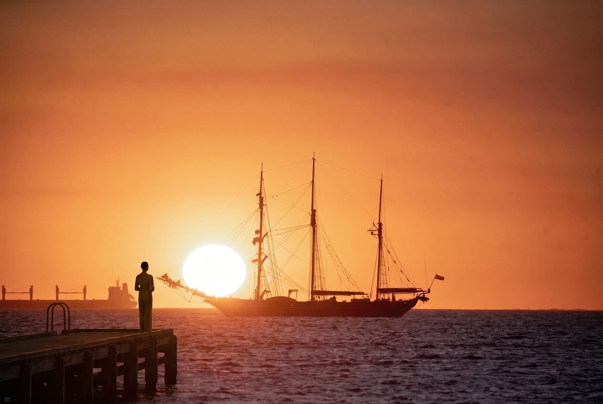 A tall ship against the setting sun at Fremantle, a guest watching from the pier