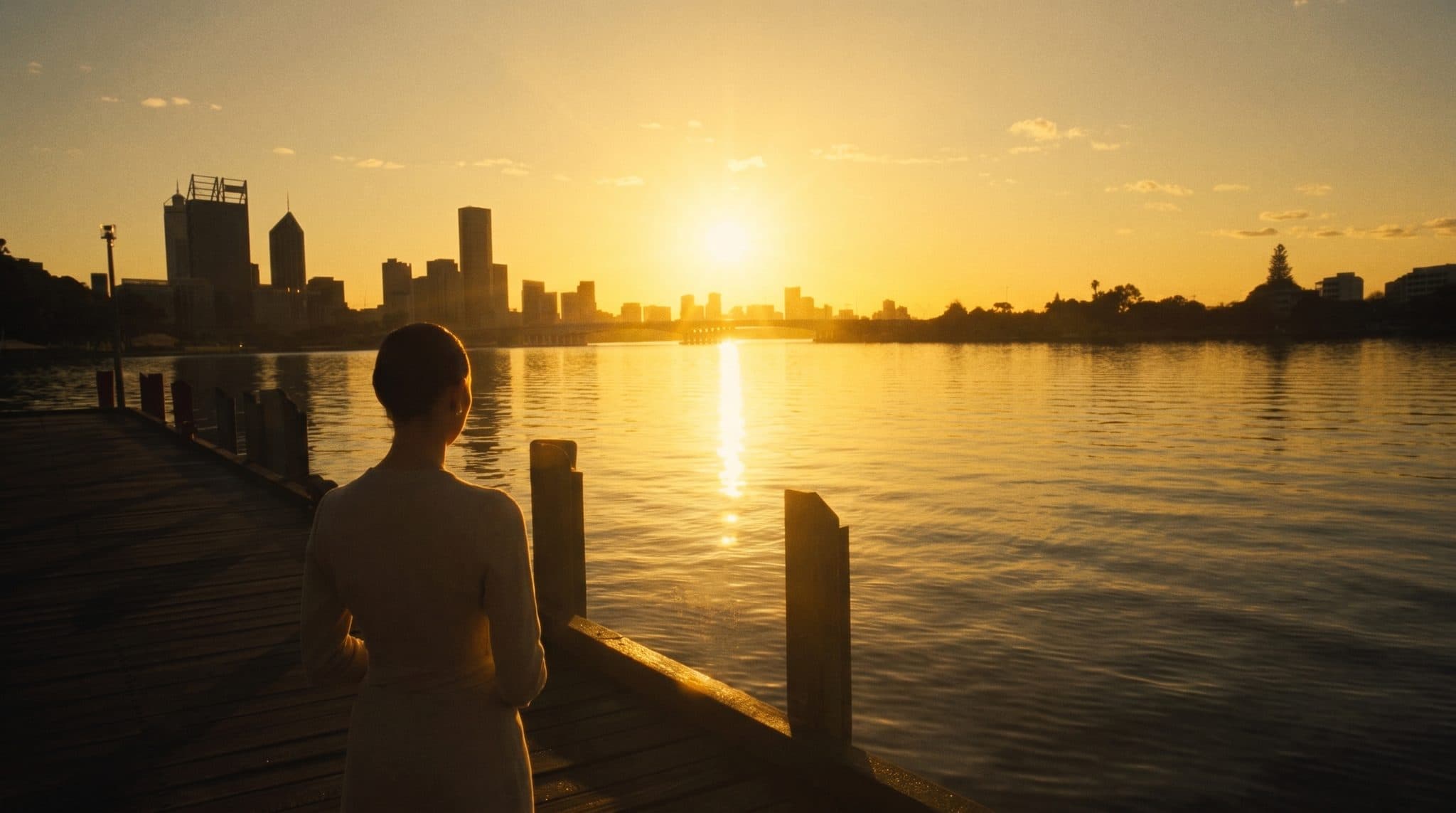 Sunrise over the Swan River, a guest in oatmeal linen watching from the jetty